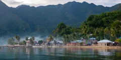 a body of water with buildings and mountains in the background