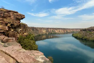 a river with a cliff and trees